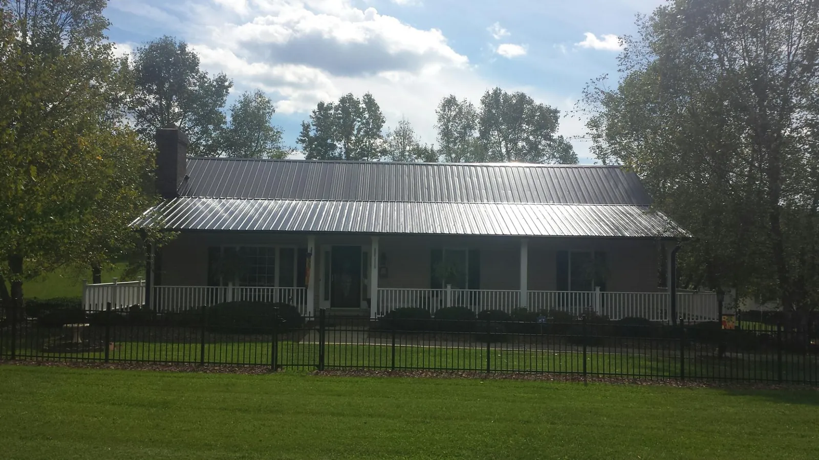 Gray metal roof on a brick ranch with a full width front porch — Gutter Guard Installation work by our crew in Brookline