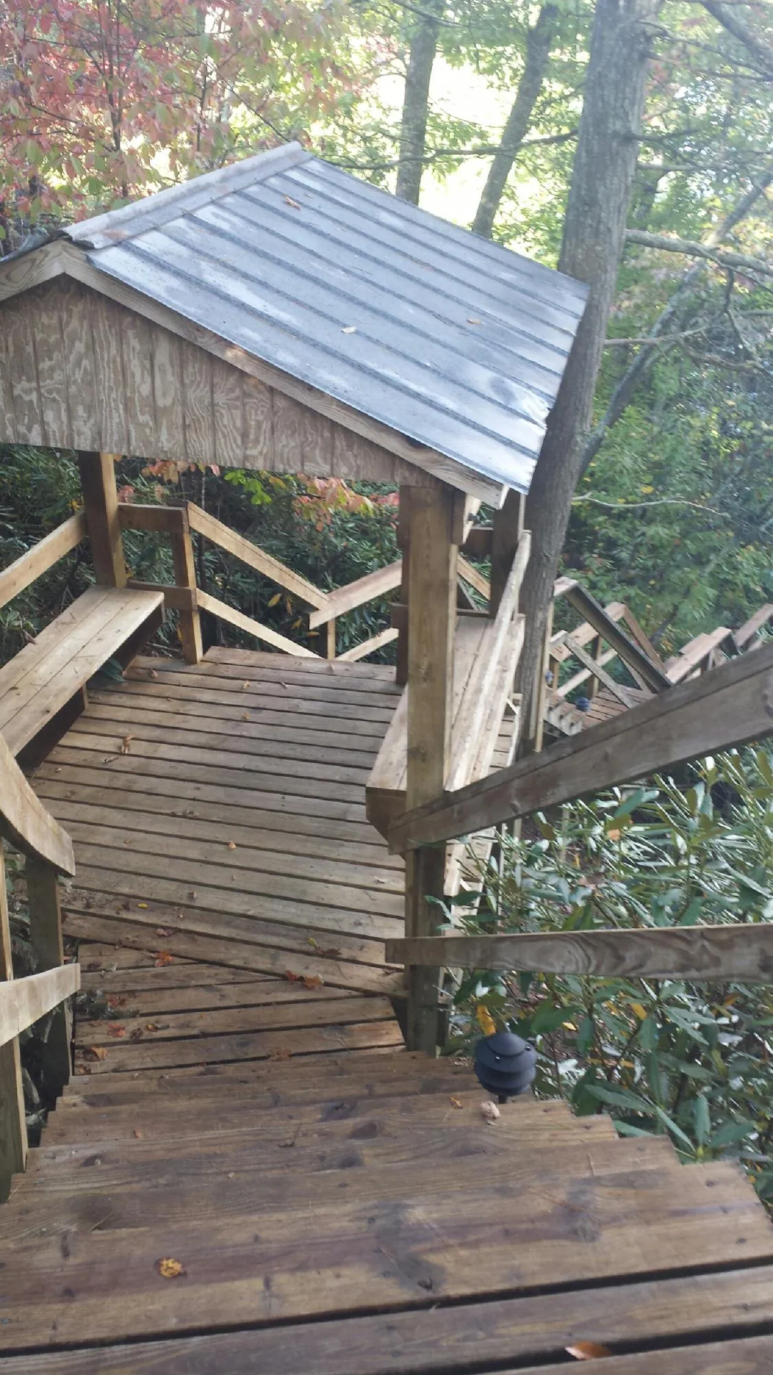 Metal roofed shelter over wooden steps on a wooded walkway — Skylight Repair & Installation work by our crew in Brookline